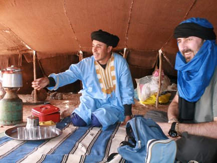 Beduine reicht marokkanischen Minztee in der Wüste – Familienreise nach Marokko