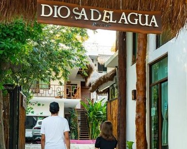 Ein Paar steht vor dem Eingang des Hotels Diosa del Agua, umgeben von üppigem Grün und einem einladenden Ambiente.