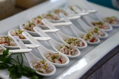 Eine elegante Anordnung von kleinen Löffeln, gefüllt mit frischem Ceviche, garniert mit Kräutern und Chili.