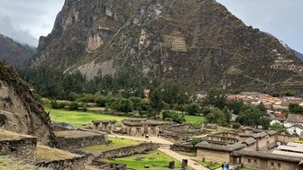 Die beeindruckende Festung Ollantaytambo liegt vor einem majestätischen Berg, umgeben von grünen Wiesen und historischen Ruinen.
