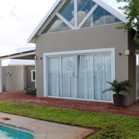 Ein Chalet der Africa Safari Lodge mit großen Fenstern und Terrasse, direkt am Pool gelegen - Namibia Familienreise