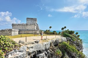 Frau steht auf den Klippen bei Tulum und blickt auf das türkisfarbene Meer – Mexiko Reise mit Kindern