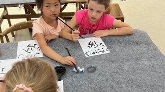 Kinder üben chinesische Kalligrafie auf Papier – China Reise mit Kindern