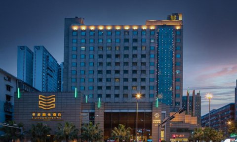 Das Tianfu Sunshine Hotel erstrahlt in der Dämmerung, umgeben von modernen Gebäuden und beleuchteten Straßenlaternen.