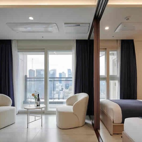 Ein modernes Hotelzimmer mit zwei Betten, einem großen Fenster und einem Balkon mit Stadtblick.