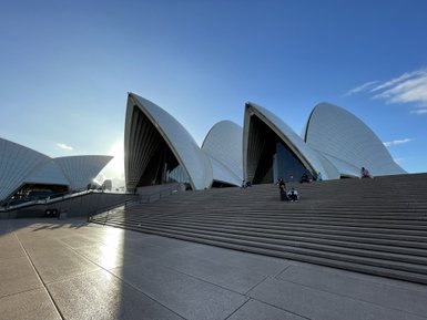 Die beeindruckende Architektur des Sydney Opera House, mit seinen charakteristischen Segel-ähnlichen Dächern, strahlt unter blauem Himmel.
