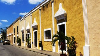 Bunte Häuserfassade mit Bögen in Gelb – Mexiko Reise mit Kindern