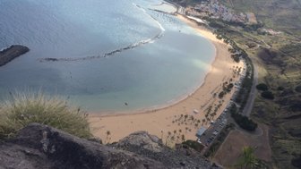 Ein atemberaubender Blick auf den goldenen Sandstrand von Las Teresitas, umgeben von klarem Wasser und sanften Hügeln.