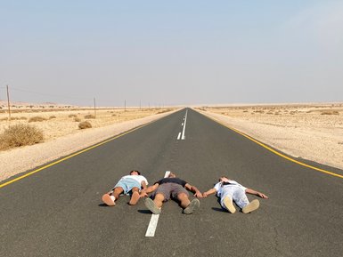 Eine Familie liegt auf einer Straße in der Wüste - Namibia mit Jugendlichen