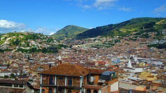 Ein atemberaubender Blick auf Quito, mit bunten Häusern und grünen Hügeln unter einem strahlend blauen Himmel.