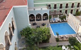 Ein ruhiger Innenhof mit einem Pool, umgeben von Palmen, Stühlen und einem Wasserbrunnen, ideal für Entspannung.
