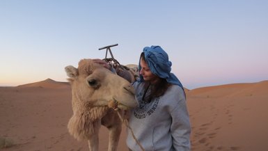 Jugendliche zeigt liebevolle Geste beim Streicheln eines Kamels – Marokko Familienreise