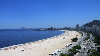 Ein weitläufiger Blick über den sonnigen Strand von Copacabana, gesäumt von Palmen und Menschen, die entspannen und Spaß haben.