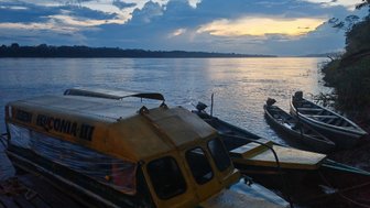 Ein gelbes Boot liegt am Ufer eines ruhigen Flusses, während die Dämmerung den Himmel in sanften Farben erleuchtet.