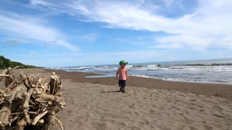 Kind spielt fröhlich am weißen Sandstrand im Tortuguero Nationalpark – Costa Rica Reise mit Kindern
