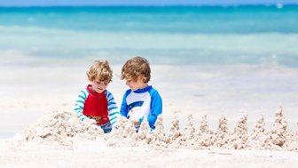Zwei Kinder formen gemeinsam eine Sandburg am Strand von Playa del Carmen – Mexiko Reise mit Kindern
