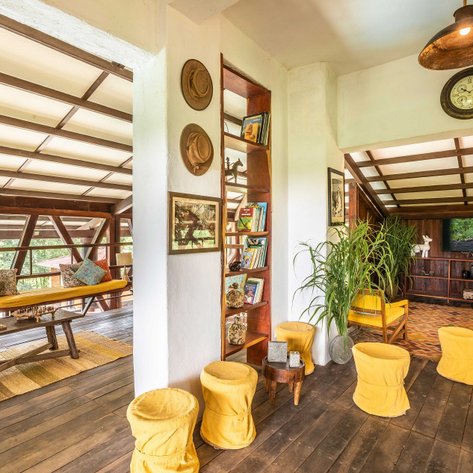 Ein einladender Lounge-Bereich mit bunten Kissen und rustikalen Möbeln, umgeben von einer grünen Landschaft.