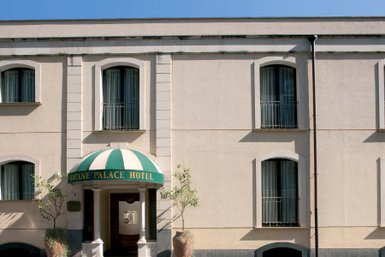 Das Katane Palace Hotel zeigt eine elegante Fassade mit einem markanten grünen und weißen Vordach und großen Fenstern.