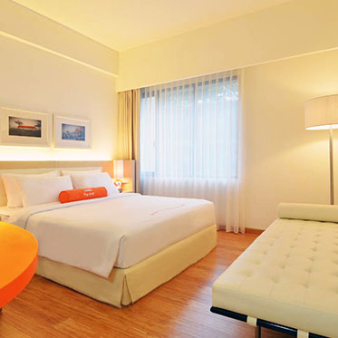 Ein modernes Hotelzimmer mit einem großen Bett, einem eleganten Tisch und einem gemütlichen Sofa in sanften Farben.