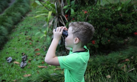 Junge beobachtet die Tierwelt mit Fernglas bei der Maquenque Eco Lodge im Sarapiquí-Tal – Costa Rica Reise mit Kindern