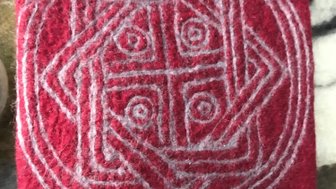 Ein rotes Filzstück mit einem komplexen, grauen Muster, das geometrische Formen und Kreise darstellt.