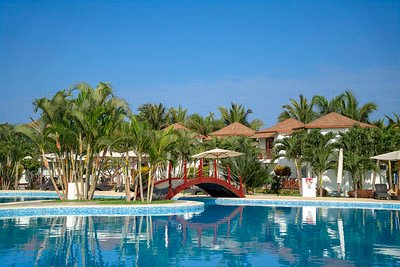 Ein ruhiger Pool mit klarem Wasser spiegelt die umliegenden Palmen und die Architektur des Resorts wider.