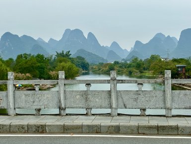 Eine malerische Landschaft mit schroffen Bergen und einem ruhigen Fluss, umgeben von üppigem Grün und sanften Hügeln.