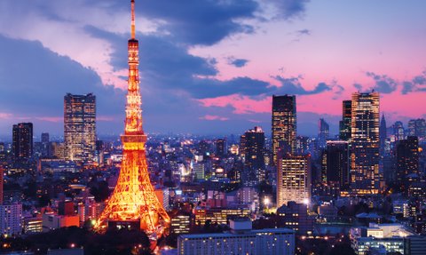 Der Tokyo Tower leuchtet in warmen Farben, während die Stadt unter einem dramatischen Abendhimmel erstrahlt.