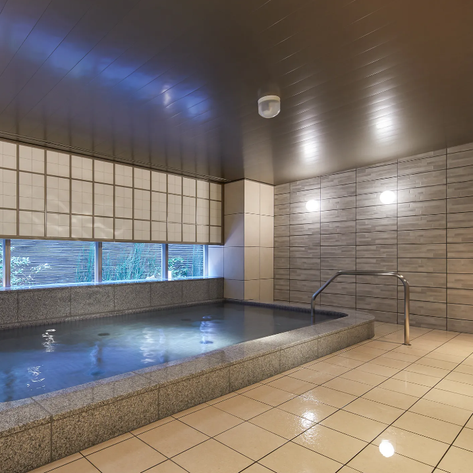 Ein eleganter Thermalbadbereich mit einem großen, ruhigen Wasserbecken und sanften Beleuchtungselementen im Hintergrund.