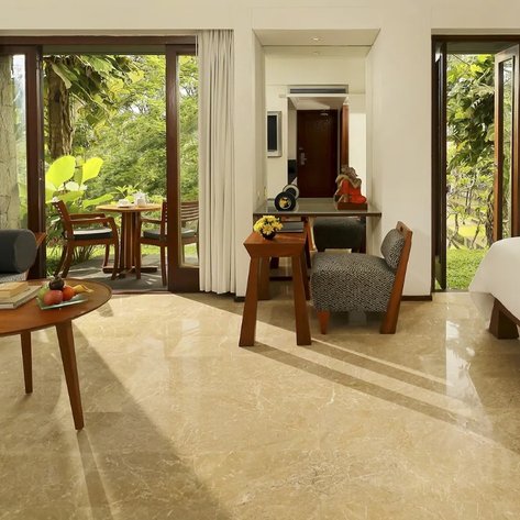 Ein elegantes Zimmer mit einem gemütlichen Sofa, einem Tisch und Blick auf die grüne Natur durch große Fenster.