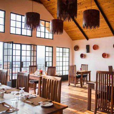 Ein stilvolles Restaurant mit Holztischen und Stühlen, großen Fenstern und einem Blick auf die Landschaft.