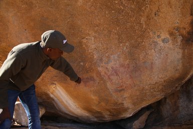 Ein Guide zeigt auf eine alte Wandmalerei und erklärt die Bedeutung - Namibia mit Kindern