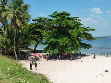 Menschen spazieren entspannt am sonnigen Sandstrand entlang und genießen das Meer – Sri Lanka Familienreise