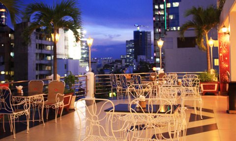 Die Terrasse des Huong Sen Hotels bietet einen atemberaubenden Blick auf die Stadt bei Dämmerung, umgeben von eleganten Stühlen.