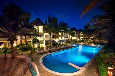 Ein beleuchteter Pool in einem Hotel, umgeben von Palmen und Liegen, strahlt eine entspannte Urlaubsatmosphäre aus.