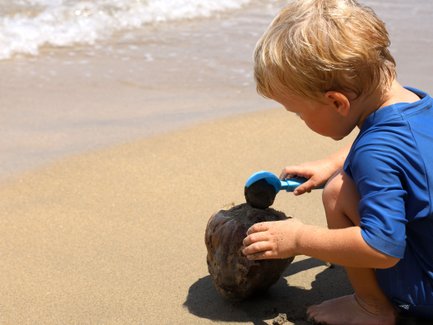 Kleines Kind spielt fröhlich im Sand am Strand – Costa Rica Familienreise