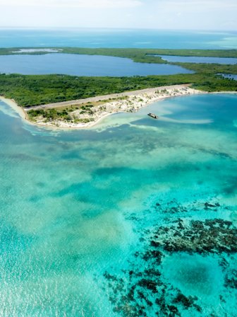 Eine atemberaubende Luftaufnahme einer tropischen Insel mit üppigem Grün und klarem, türkisfarbenem Wasser umgeben.