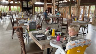 Fröhliches Kind sitzt im Restaurant der Garden Route Game Lodge und lächelt – Garden Route Familienreise