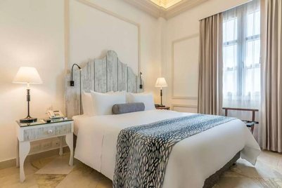 Ein elegantes Hotelzimmer mit einem großen Bett, sanften Farben und stilvollen Lampen, die eine gemütliche Atmosphäre schaffen.