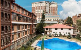 Ein einladender Pool umgeben von gepflegten Gärten und modernen Gebäuden, ideal für Familienurlaube in Nepal.