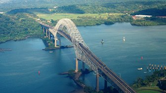 Eine beeindruckende Brücke überspannt das Wasser, umgeben von üppigem Grün und sanften Hügeln im Hintergrund.