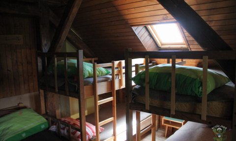 Ein gemütlicher Schlafraum mit Etagenbetten, Holzverkleidung und großen Fenstern, die Tageslicht hereinlassen.