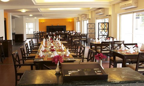 Ein elegantes Restaurant mit Holzstühlen und Tischen, dekoriert mit frischen Blumen und stilvoll eingedeckten Tischen.