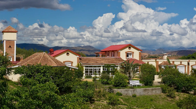 Eine malerische Lodge mit roten Dächern, umgeben von üppigem Grün und majestätischen Wolken am Himmel.