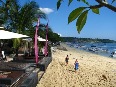 Besucher genießen den Strand, während Boote auf dem Wasser vor Nusa Lembongan liegen – Bali Familienreise