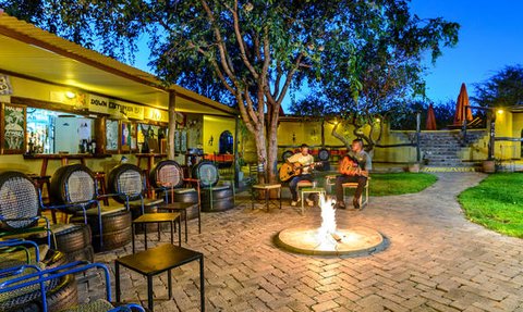 Zwei Musiker spielen Gitarre am Lagerfeuer, umgeben von gemütlichen Sitzgelegenheiten und einer einladenden Atmosphäre.