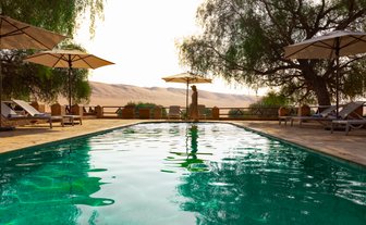 Erfrischender Pool im Thousand Nights Camp mit Blick auf die goldenen Sanddünen – Oman mit Kindern