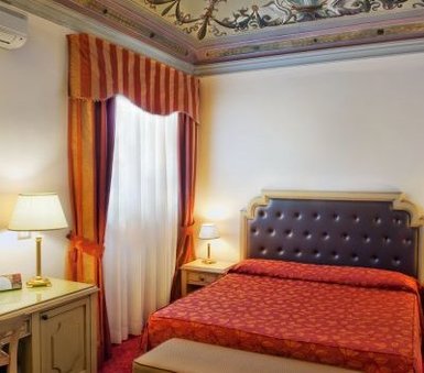 Ein elegantes Hotelzimmer mit einem großen, gepolsterten Bett und einem kunstvoll verzierten Deckenmuster.
