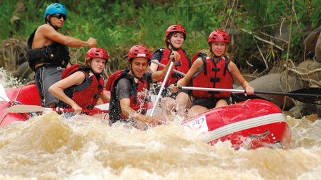 Gemeinsam paddelnde Gruppe im roten Rafting-Boot – Costa Rica Reise mit Kindern