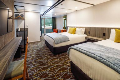 Zwei komfortable Betten mit hellen Kissen und einer warmen Decke in einem modernen Hotelzimmer.
